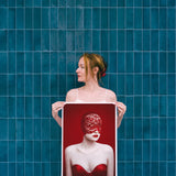 Woman holding a framed artwork against a blue tiled wall