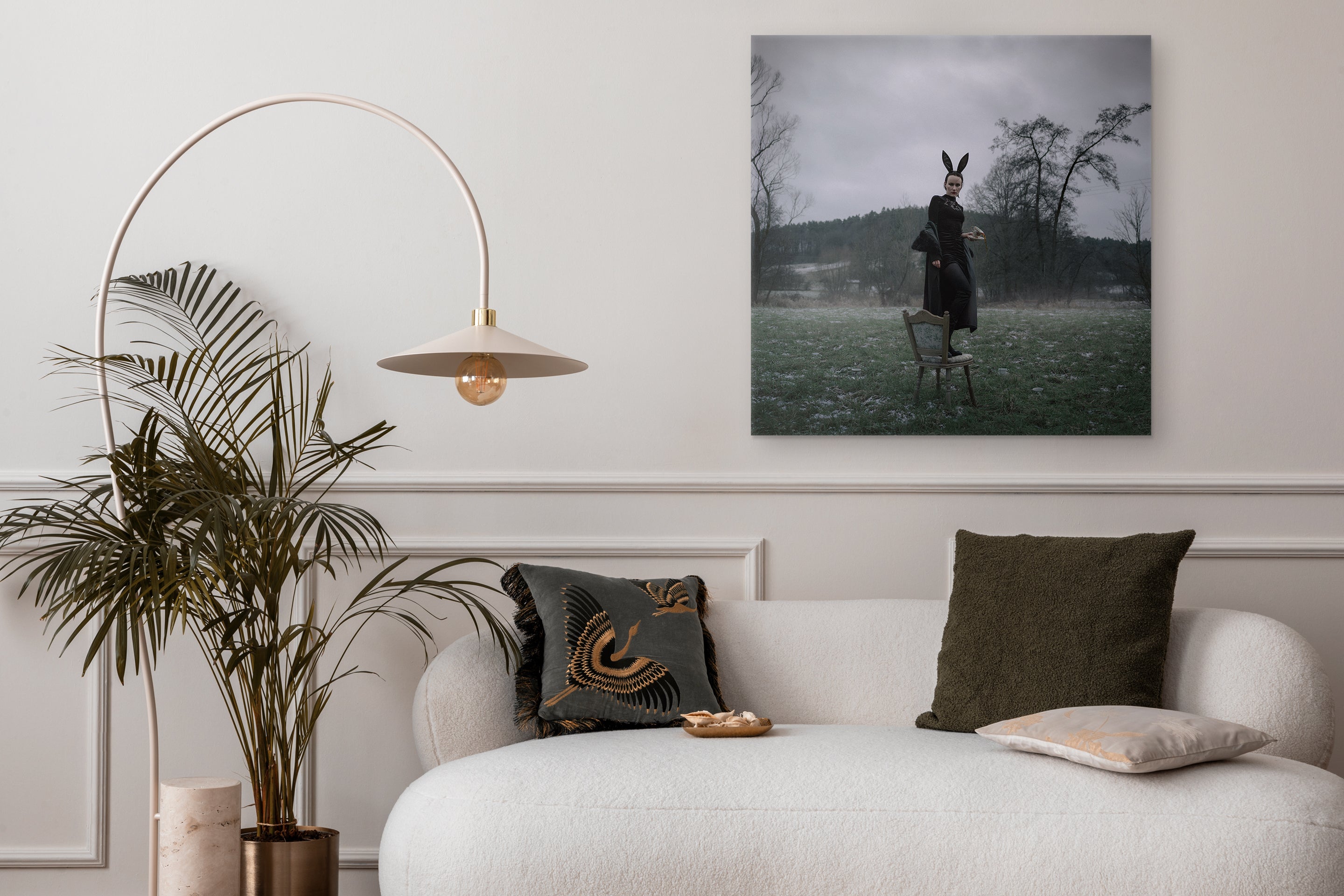 Modern living room with a white sofa, decorative pillows, a plant, and a wall art piece.