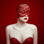 Woman wearing a red lace head covering and red dress against a red background