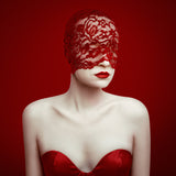 Woman wearing a red lace head covering and red dress against a red background