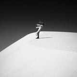 Person sitting on a sand dune with a minimalistic black and white color scheme