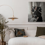 Modern living room with a white sofa, decorative pillows, a plant, and a wall art piece.