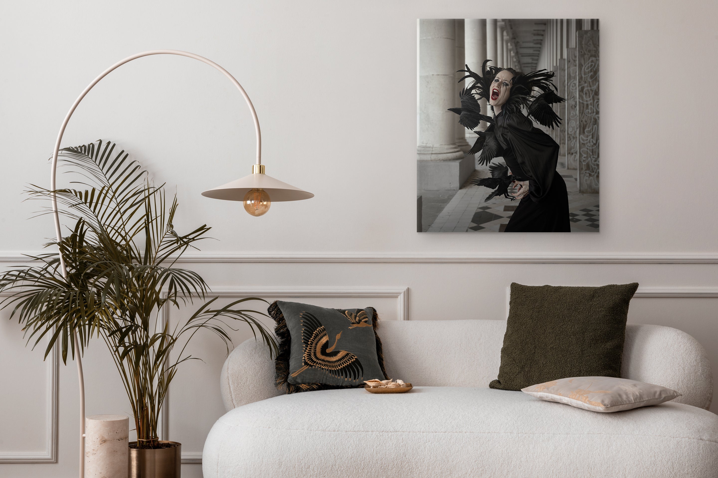 Modern living room with a white sofa, decorative pillows, a plant, and a wall art piece.