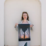 Woman holding a large photograph against a light-colored wall.