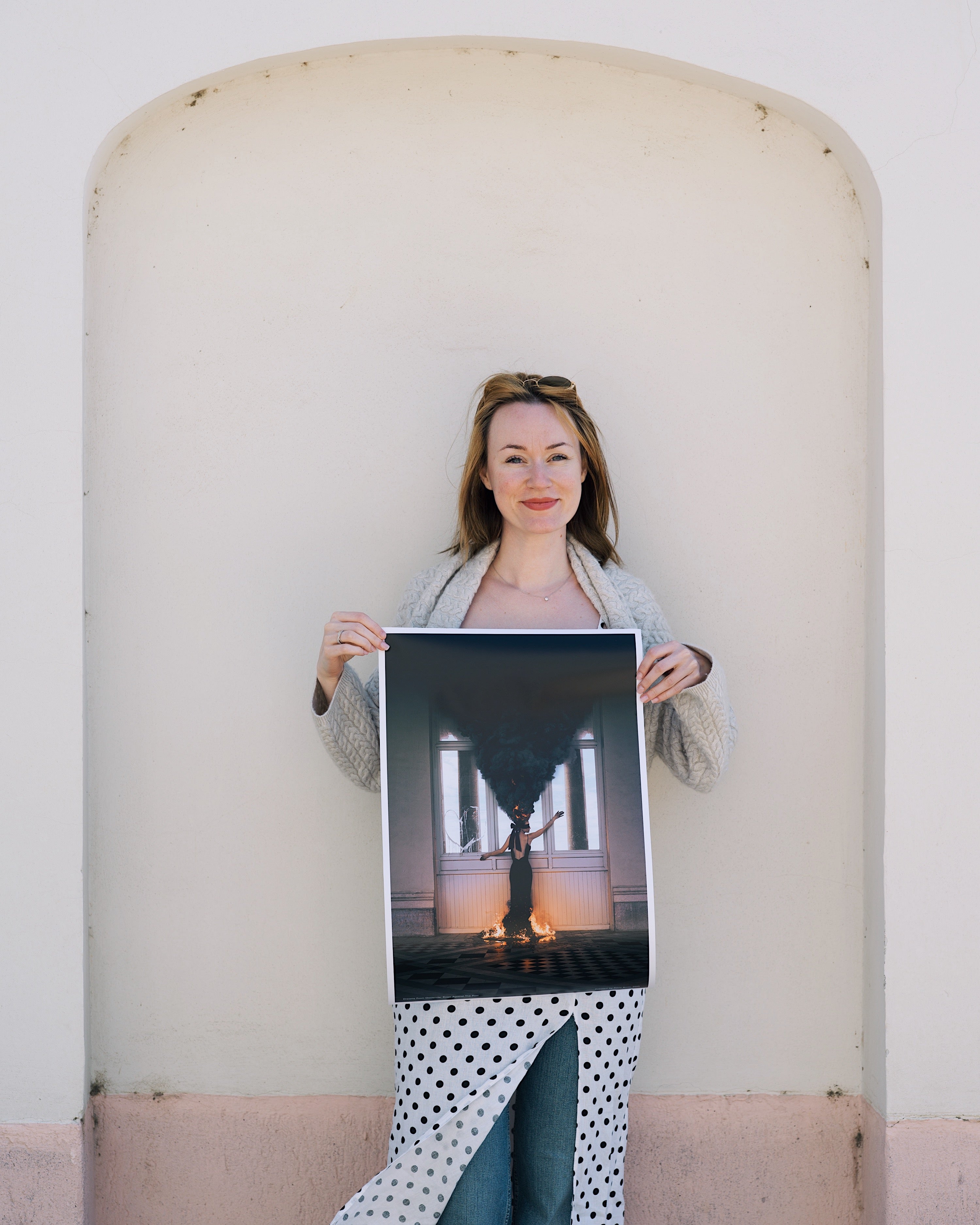 Woman holding a large photograph against a light-colored wall.