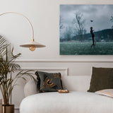 Living room with a sofa, decorative pillows, a plant, and a wall art piece.
