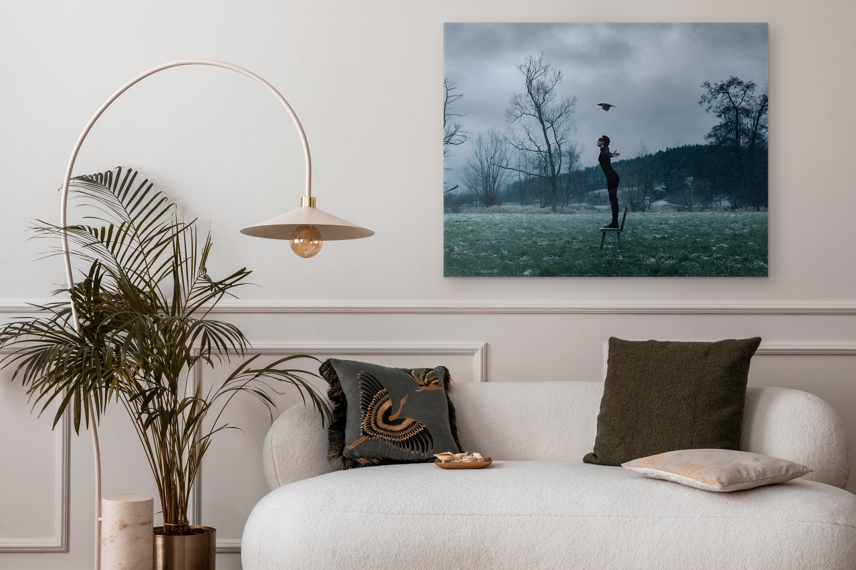 Living room with a sofa, decorative pillows, a plant, and a wall art piece.