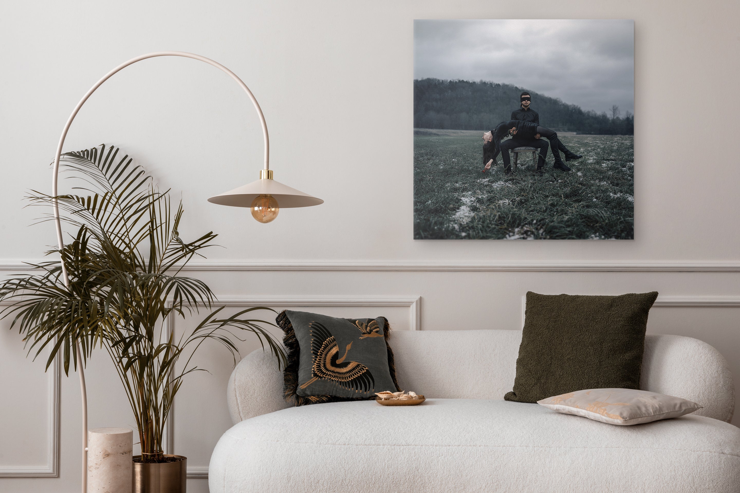 Living room with a white sofa, decorative pillows, a plant, and a wall art piece.
