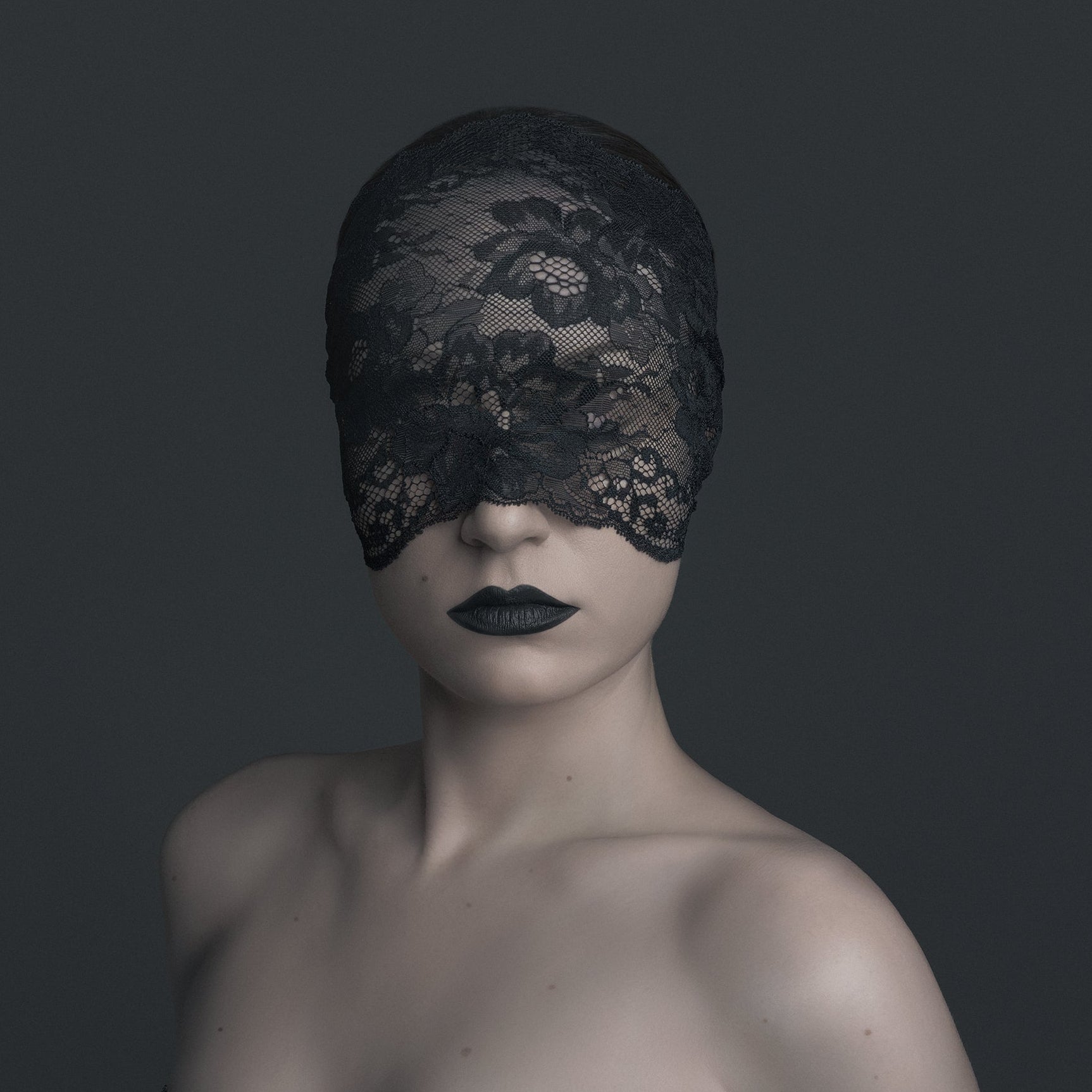 Person wearing a black lace mask and dress against a dark background