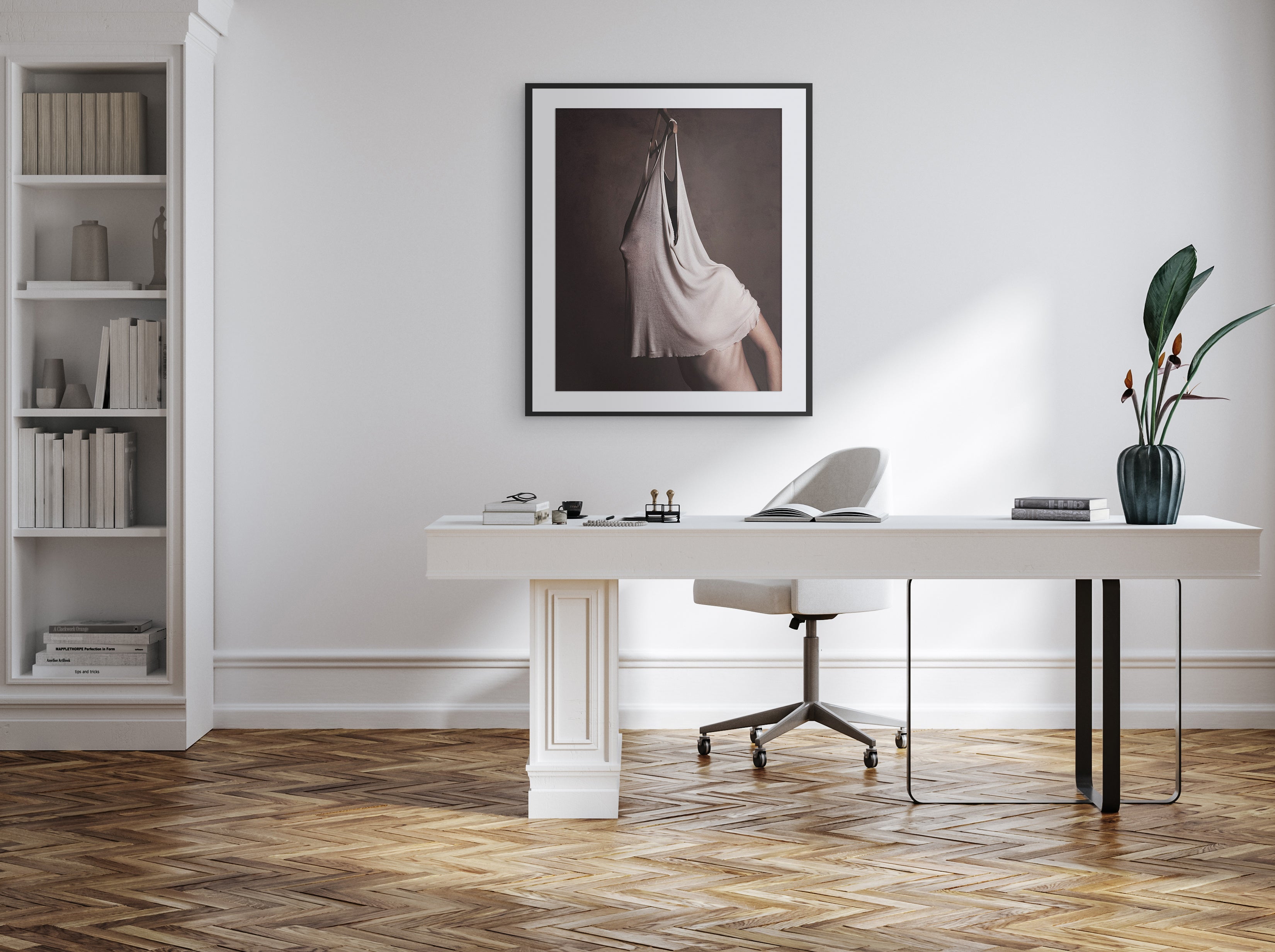 Modern office desk with chair, books, and decor in a room with a white wall and wooden floor.