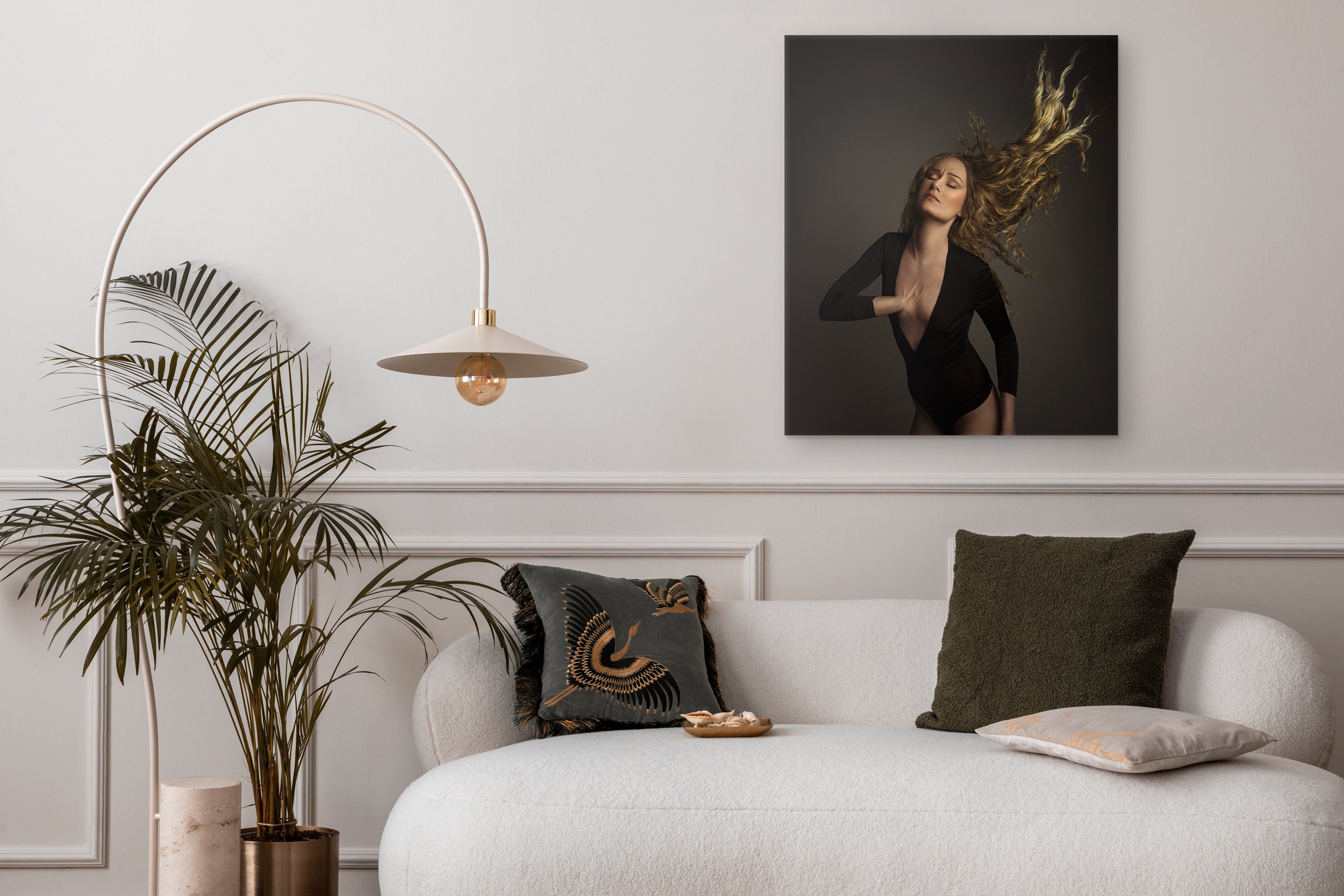 Modern living room with a white sofa, decorative pillows, a plant, and a wall art piece.